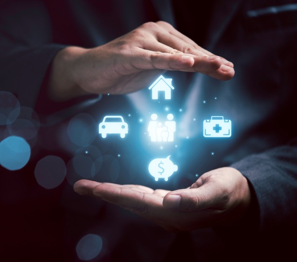 Two hands holding a holographic projection of icons representing a house, car, piggy bank, family, and medical kit.
